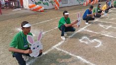 some people are sitting on the ground with bunny ears and holding signs in their hands