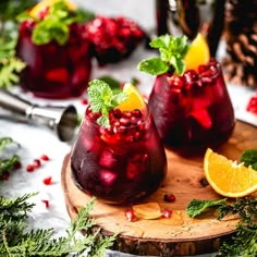 two glasses filled with pomegranate and garnish sitting on a cutting board