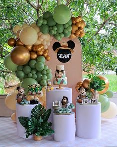 a table topped with lots of balloons and cake next to potted plants on top of white pedestals