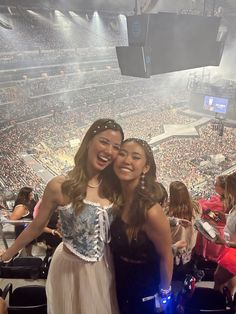 two women standing next to each other in front of a crowd at a sporting event