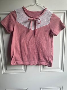 This vintage 1970's girls t-shirt has a white yoke with a pink bow.  It is a little dressy compared to the normal t-shirts. Bust-28 inches Length- 18 inches Sleeve-6 inches To see more of our vintage 1970's clothing inventory as well as our other vintage items please visit our store at ChoiceRecycling.  We add new items every week. Thank you, Karmyn Casual Short Sleeve Top With Pink Bow, Casual Crew Neck Top With Pink Bow, White Cotton Top With Pink Bow, Retro Pink Short Sleeve Top, Cotton Top With Pink Bow And Short Sleeves, Crew Neck Cotton Top With Pink Bow, Retro Pink Shirt With Buttons, Short Sleeve Cotton Top With Pink Bow, Cotton Short Sleeve Top With Pink Bow