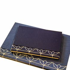 two folded notebooks with gold trim and blue covers, one on top of the other