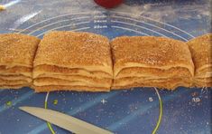 a stack of crepes sitting on top of a cutting board next to a knife