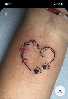 a small tattoo on the arm of a woman's leg with a heart and paw prints