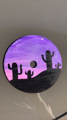 a purple and black painted disc with cactus silhouettes