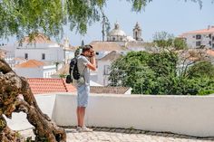 a man standing on top of a roof talking on a cell phone while wearing a backpack