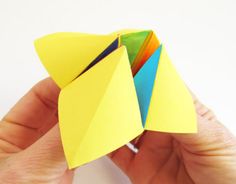 a hand holding an origami bird made out of folded paper and colored papers