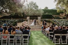 a bride and groom standing at the end of their wedding ceremony in front of an outdoor garden