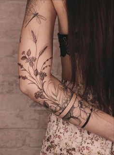 a woman's arm with flowers and dragonflies on it