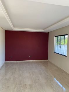 an empty room with red walls and white trim on the wall is seen in this image