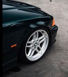 the front end of a black car with white rims and spokes on it