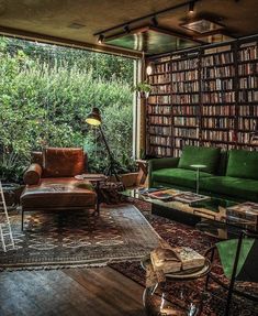 a living room filled with green furniture and lots of books on the shelves in front of it