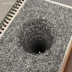 an open spiral notebook with black and white doodles on the cover, showing a hole in the middle