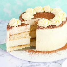 a cake with white frosting is on a plate and has one slice cut out