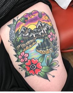 a woman's thigh with an image of mountains and flowers on the bottom half