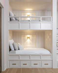 there is a bunk bed in the room with white drawers on each side and two sets of pillows on top