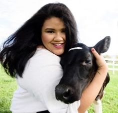 a woman is holding a black and white cow