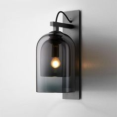 a light that is on the wall next to a glass lamp shade and black metal frame