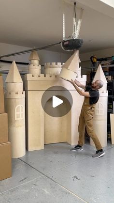 a man standing in front of a castle made out of cardboard boxes