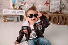 a little boy wearing sunglasses and a leather jacket