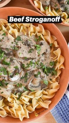 an orange bowl filled with pasta covered in mushrooms and parmesan cheese on top of a wooden table