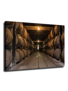 barrels are stacked in the middle of an old warehouse with light shining on them and one person standing at the far end