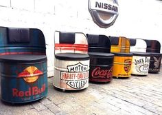 several different colored buckets are lined up on the sidewalk near a wall with a nissan logo above them