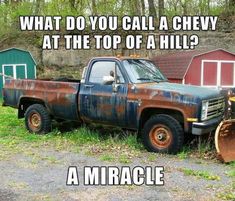 an old rusted truck parked in front of some red barns with the caption, what do you call a chevy at the top of a hill?