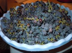 a blue bowl filled with grapes on top of a table