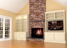 an empty living room with a stone fireplace and built - in entertainment center is shown