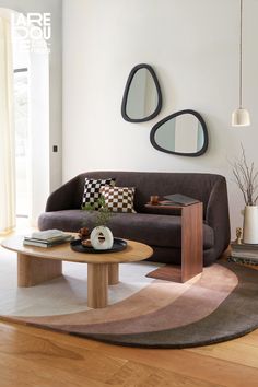 a living room with two mirrors on the wall and a coffee table in front of it