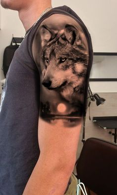 a man wearing a sleeve tattoo with a wolf on it's left arm and chest