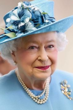 an older woman wearing a blue hat and pearls