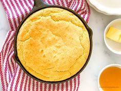 a pie in a cast iron skillet on a red and white towel next to two bowls of butter