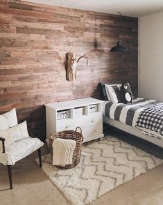 a bed room with a neatly made bed next to a wooden wall and a white dresser