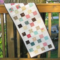 a quilt hanging on a wooden rail next to a tree