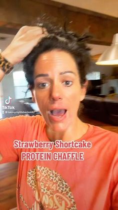 a woman making a funny face while holding her hair in front of her head with the caption strawberry shortcake protein chaffle