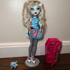 there is a doll next to a pink toy and a red plastic object on the floor