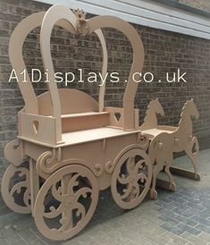 a wooden toy horse drawn carriage sitting in front of a brick wall