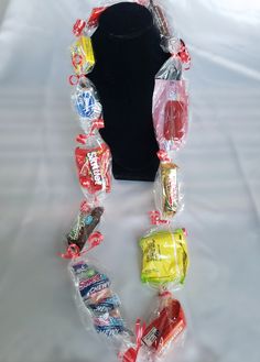 a black mannequin with candy and candies in plastic bags on it's neck