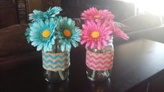 two vases with flowers in them sitting on a table