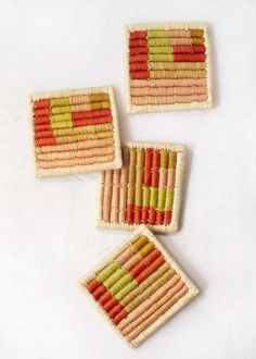 three woven coasters with different colors and designs on the edges, sitting on a white surface