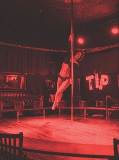 a woman is doing tricks on a pole in the middle of a circus ring with chairs around