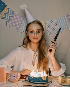 a woman sitting at a table with a birthday cake and candles in front of her