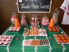 a table topped with lots of desserts and candies next to a chalkboard