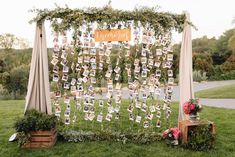 an outdoor wedding ceremony setup with pictures and flowers on the grass, surrounded by greenery