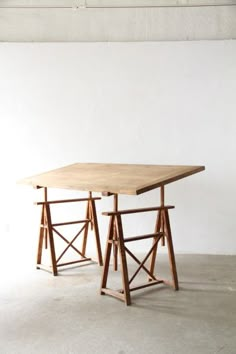 two wooden tables sitting on top of each other in an empty room with white walls