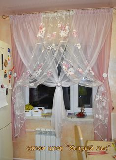 a kitchen window with sheer curtains and flowers