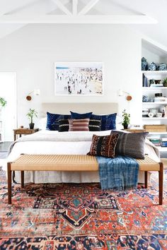 a large bed sitting in the middle of a room with lots of pillows on top of it