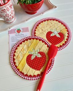 two red and yellow patchwork placemats on a table next to a potted plant